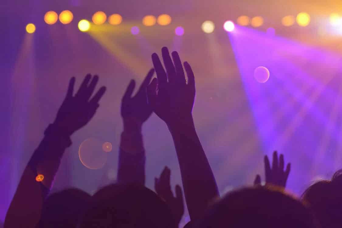 Silhouettes of hands in purple yellow light concert