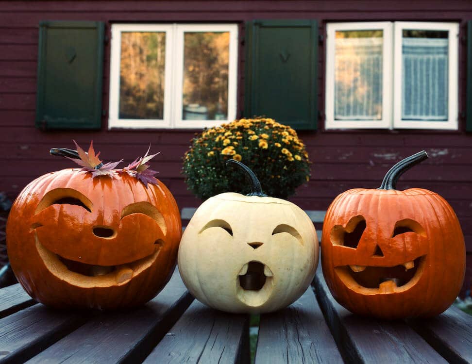 Two orange one white jack o'lanterns on porch