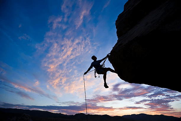 A climber is overcoming his fear by abseiling down a mountain