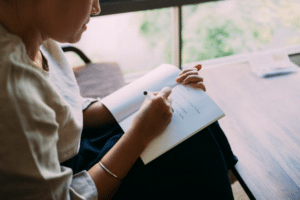 A female writing her daily journal prompts