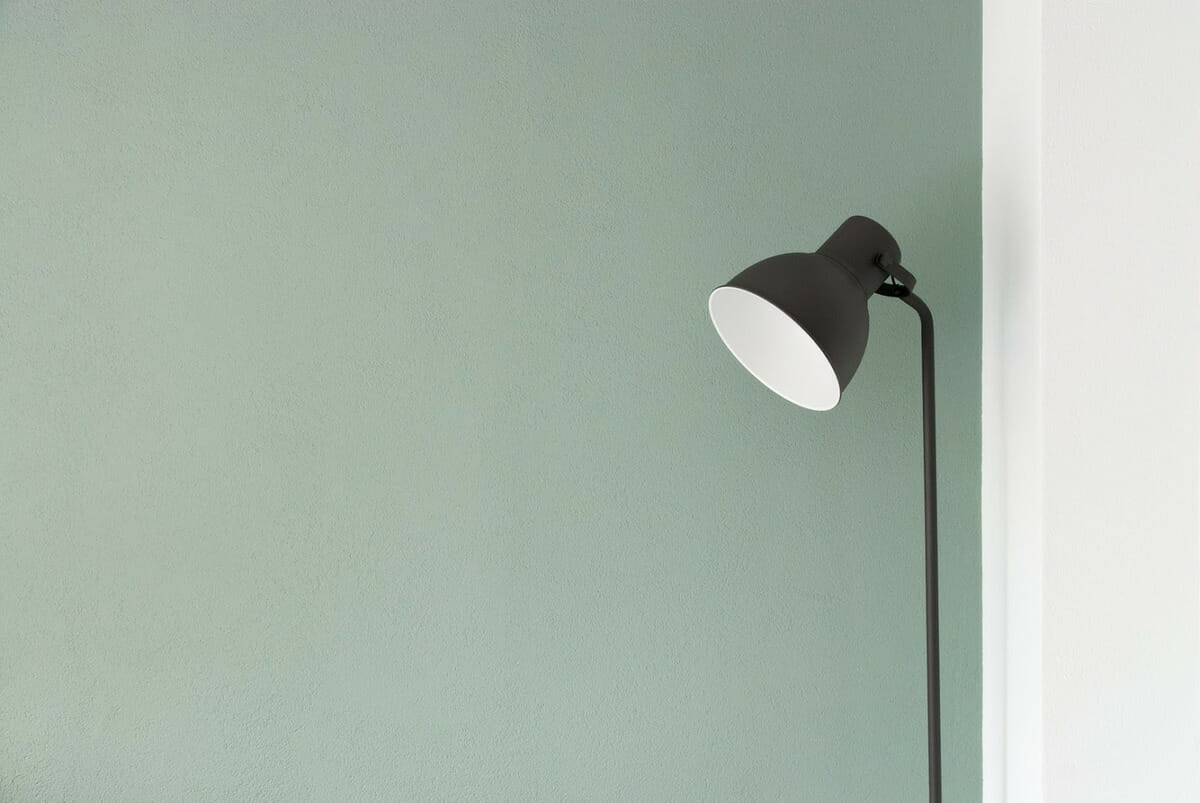 A green wall with a black floor lamp